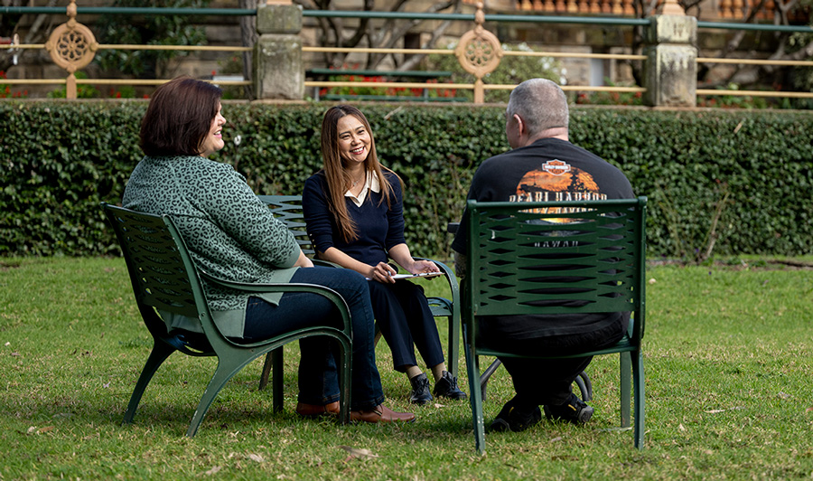 Three people participating in a mental health day program outside surrounded by gardens